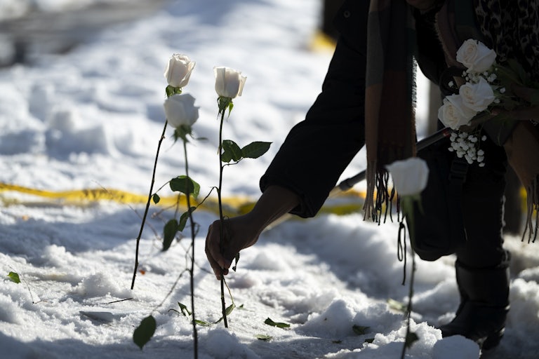 A person puts a white rose in the snow where a person was shot dead by an ICE agent in Minneapolis, Minnesota