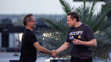 T-Mobile CEO Mike Sievert shakes the hand of Tesla's Elon Musk at an event in Boca Chica Beach, Texas.