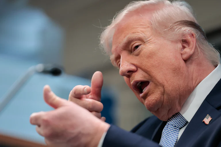 President Donald Trump speaks and makes a hand gesture as if he's about to shoot someone with a sniper.