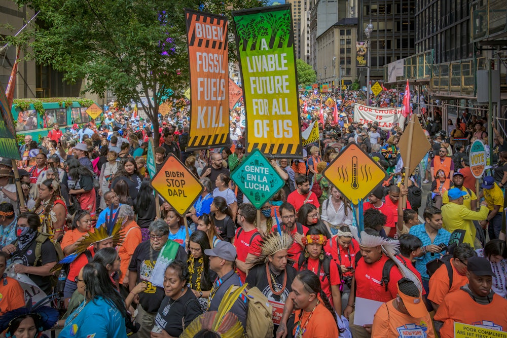 Activists holding brightly colored signs, including those reading "livable future for all of us" and "fossil fuels kill."