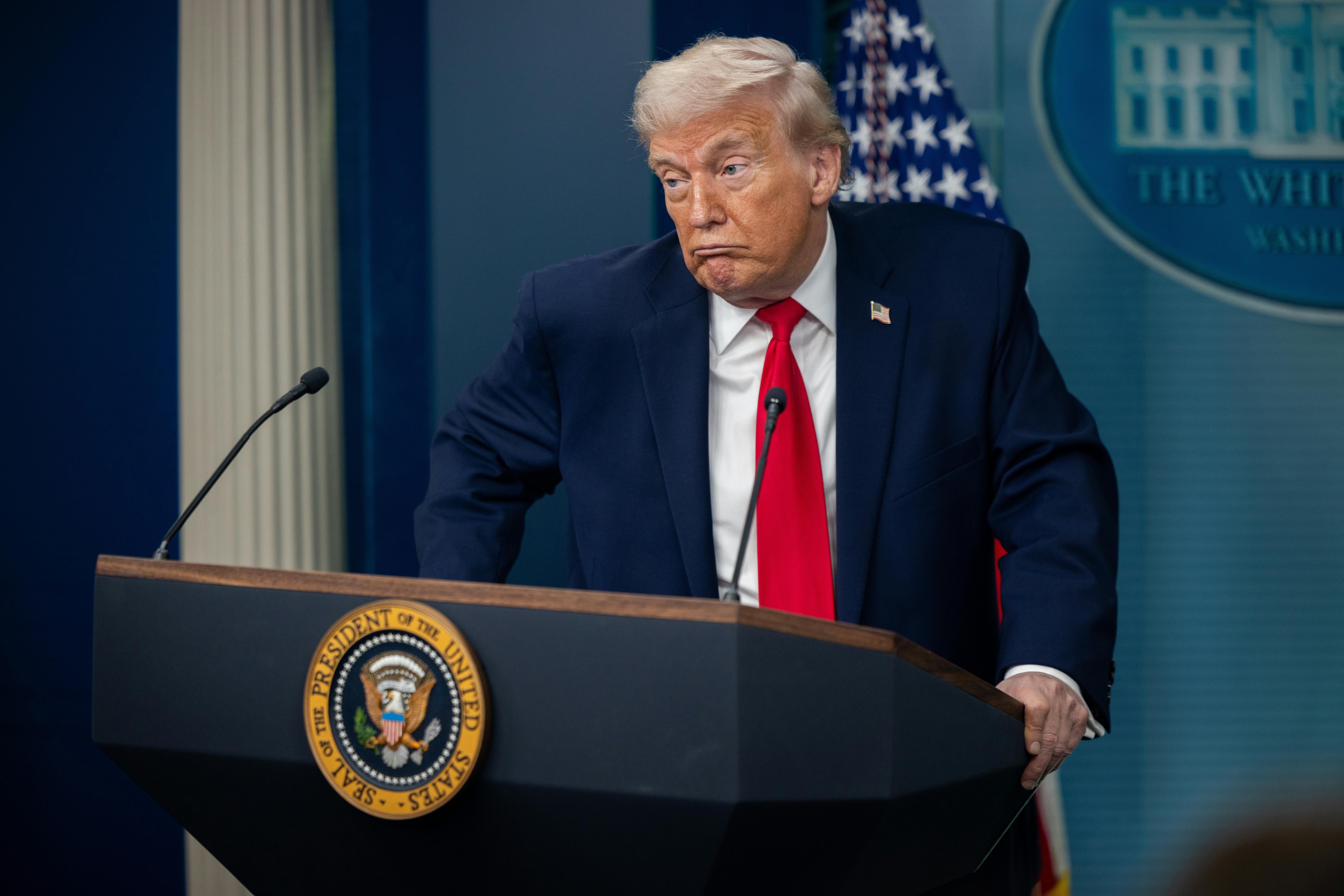 Donald Trump makes a face while standing at the podium in the White House press briefing room