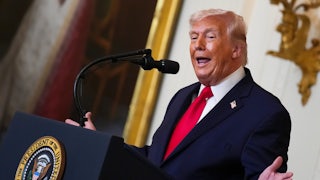 Donald Trump gestures with both hands while speaking at a podium