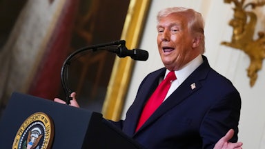 Donald Trump gestures with both hands while speaking at a podium