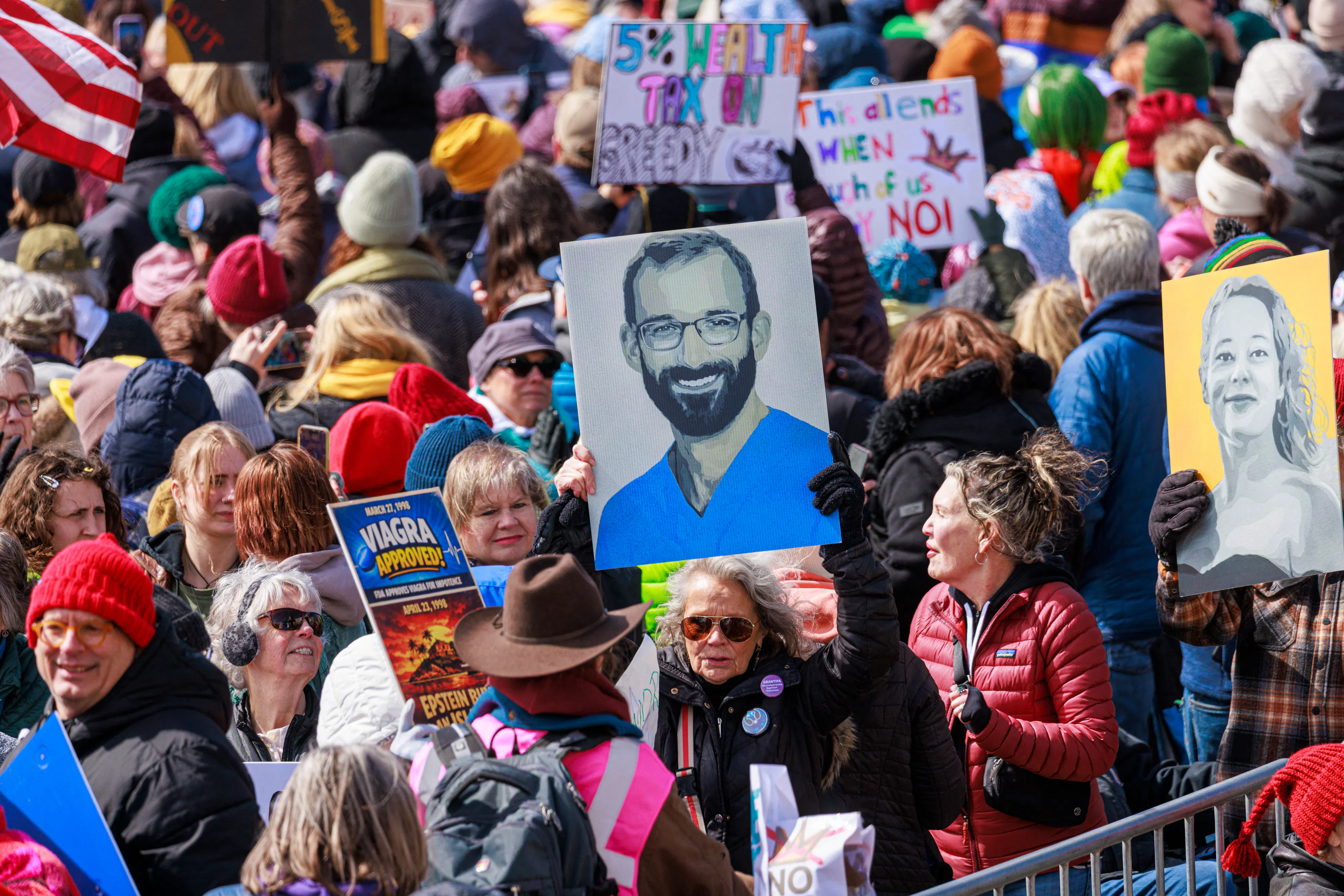 People hold up portraits of Alex Pretti and Renee Nicole Good during the No Kings protest in Minneapolis, Minnesota
