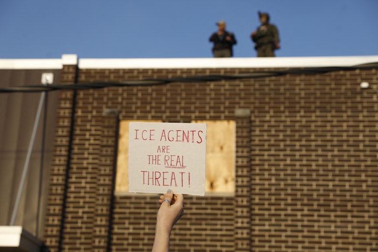 A person holds up a sign that says, "ICE agents are the real threat" at a protest