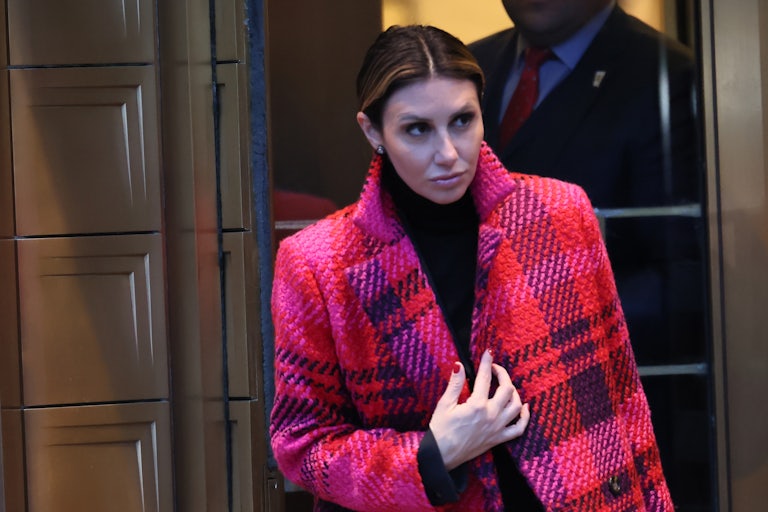 Trump lawyer Alina Habba exits a building while holding her coat lapels.