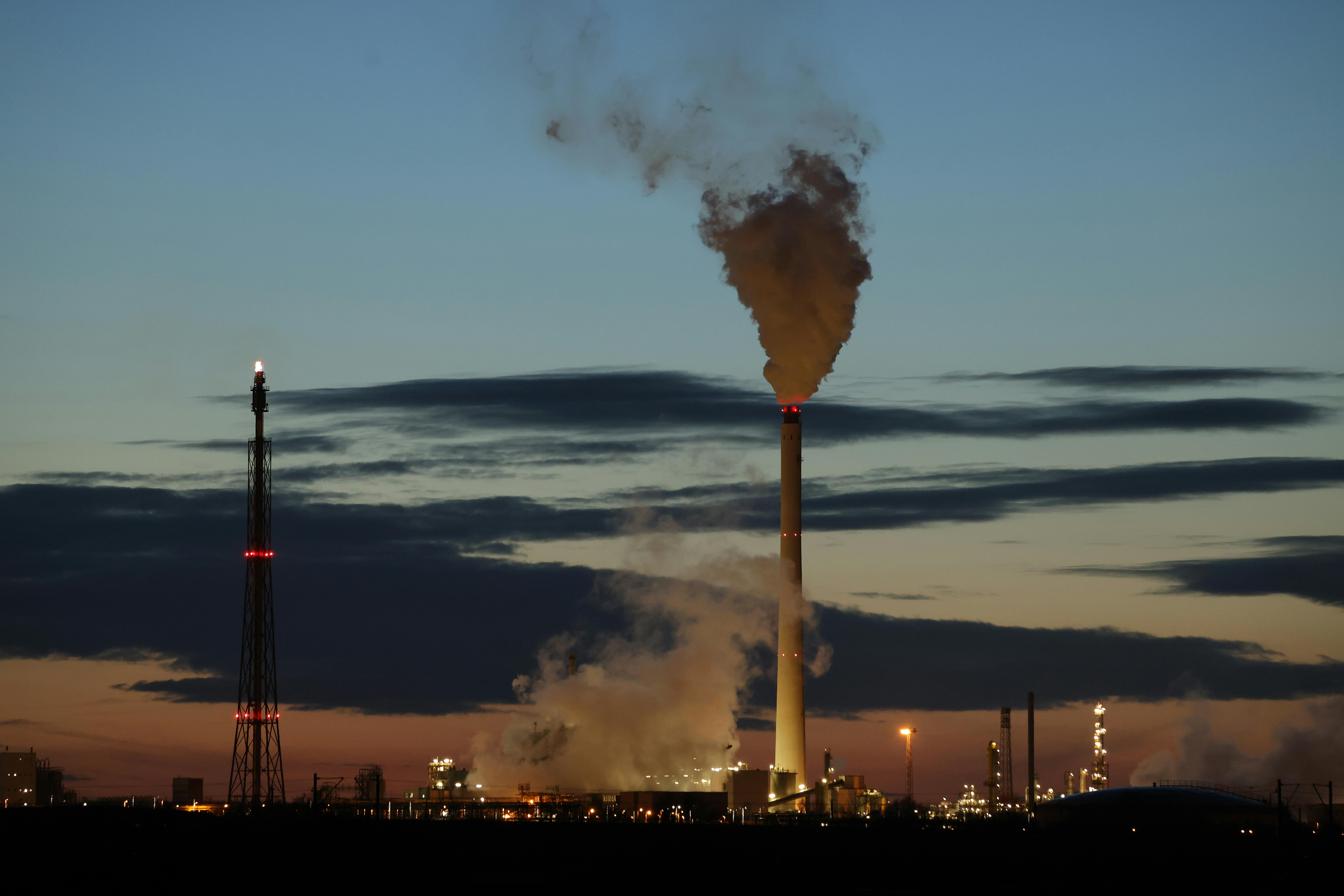 Smoke rises from refinery towers.