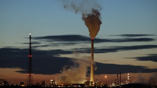 Smoke rises from refinery towers.