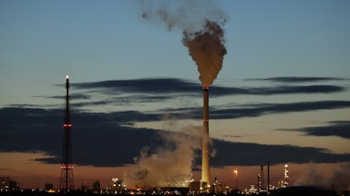 Smoke rises from refinery towers.