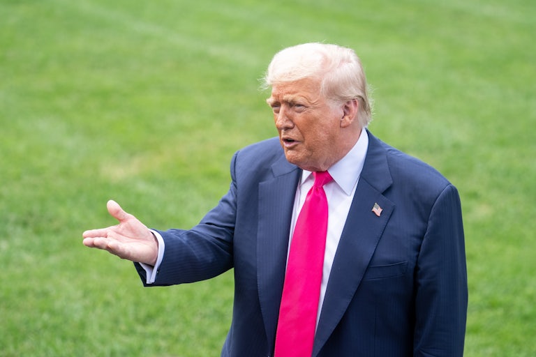 Donald Trump holds his hand out while speaking to reporters outside the White House