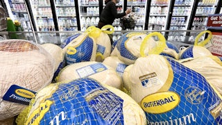 A shopper walks past turkeys displayed for sale in a grocery store ahead of the Thanksgiving holiday.