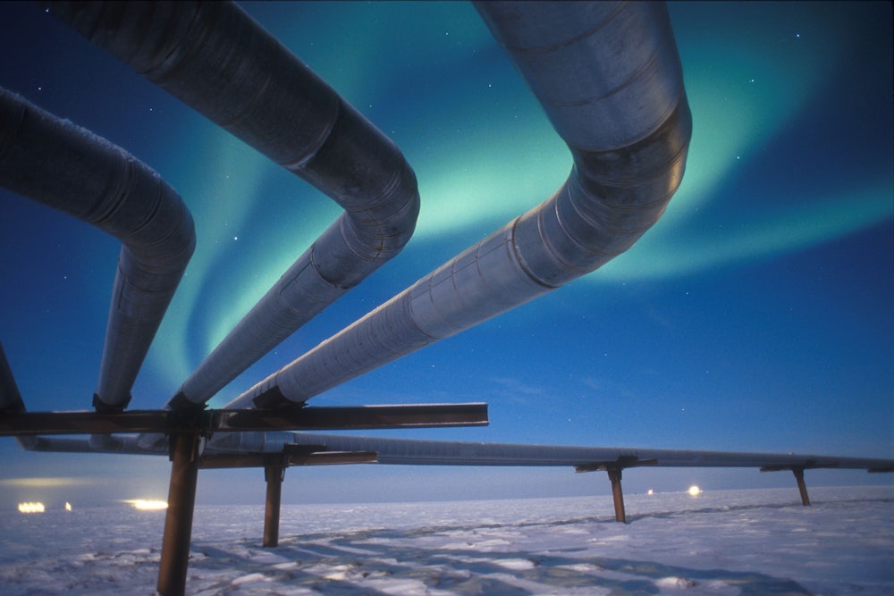 The Alaskan pipeline appears beneath the Aurora Borealis near Milne Point, Alaska.
