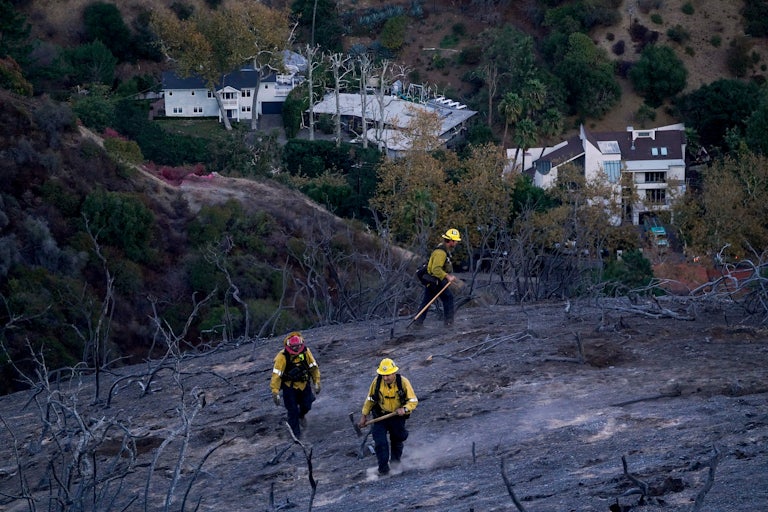 Firefighters walk in a burned out area of a Los Angeles, California, neighborhood