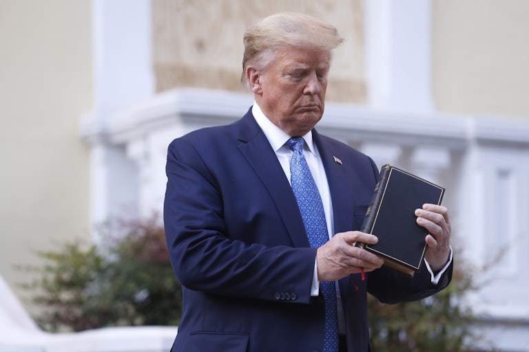 Donald Trump looks down at a Bible in his hands. (This photo is from 2020 during the height of the Black Lives Matter protests.)
