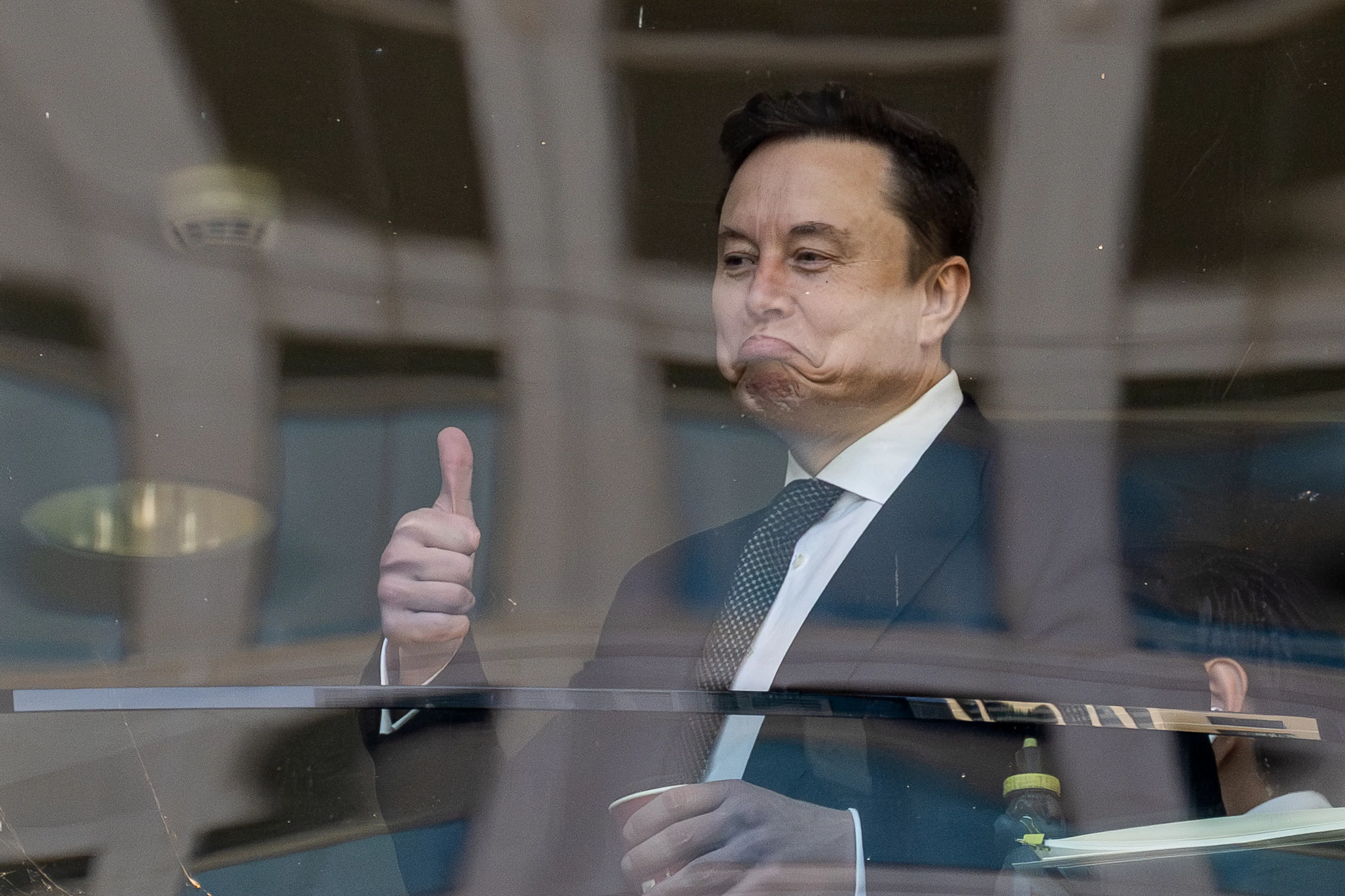 Elon musk frowns and gives a thumbs up