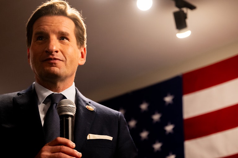 Dean Phillips holds a microphone and stands in front of an American flag