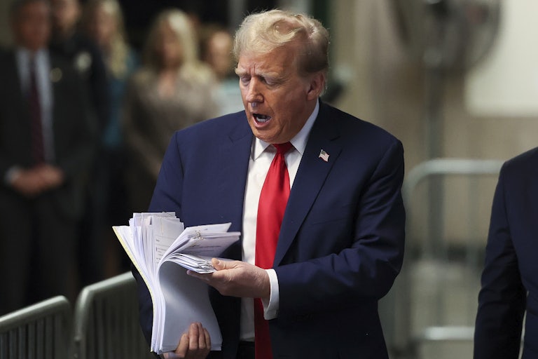 Trump holds a bunch of papers and talks