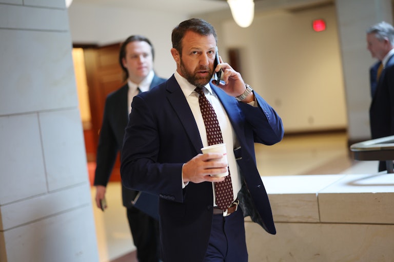 Senator Markwayne Mullin holds a coffee cup in one hand and a phone in his other.