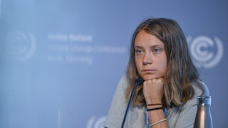 Greta Thunberg leans her head on her hand.
