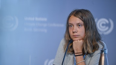 Greta Thunberg leans her head on her hand.