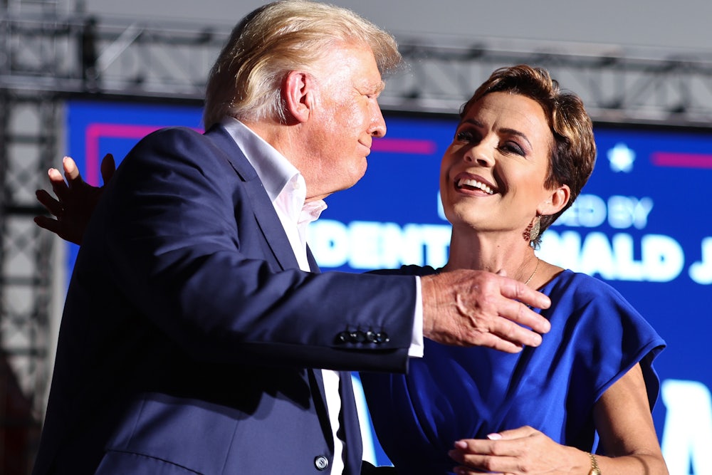 Donald Trump and Kari Lake go in for a hug. They are smiling.