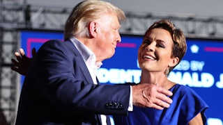 Donald Trump and Kari Lake go in for a hug. They are smiling.