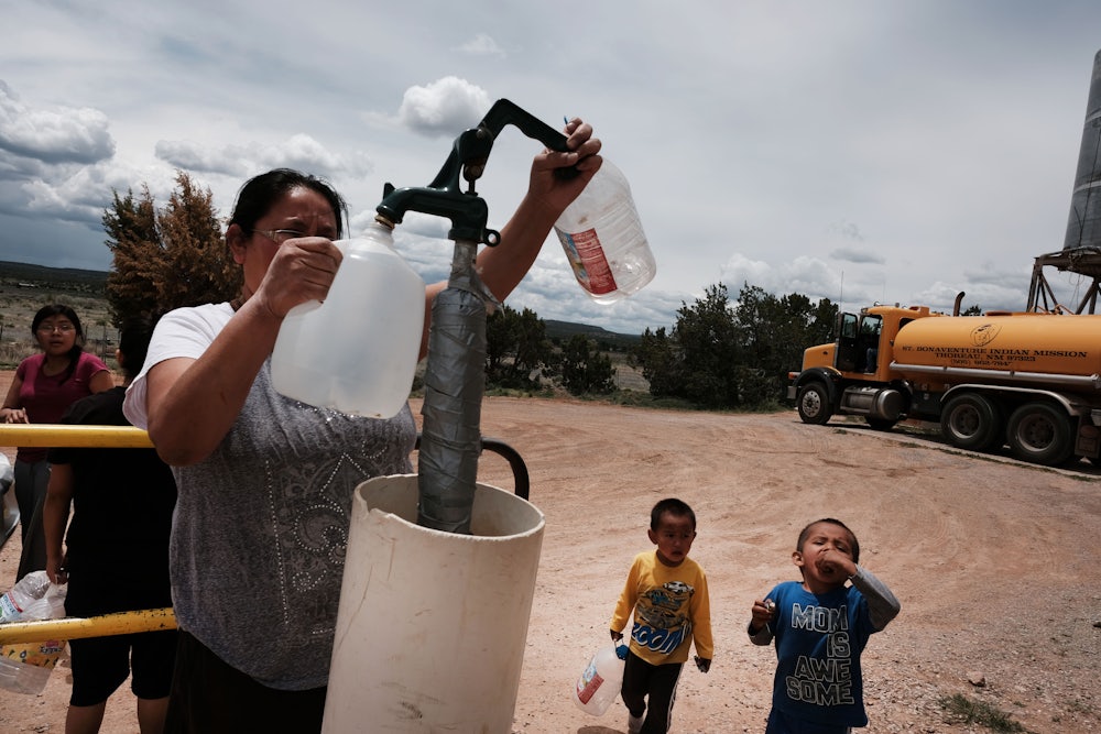 A woman fills water jugs at a public tap.