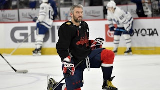 Washington Capitols player Alex Ovechkin kneels on one knee at center ice.