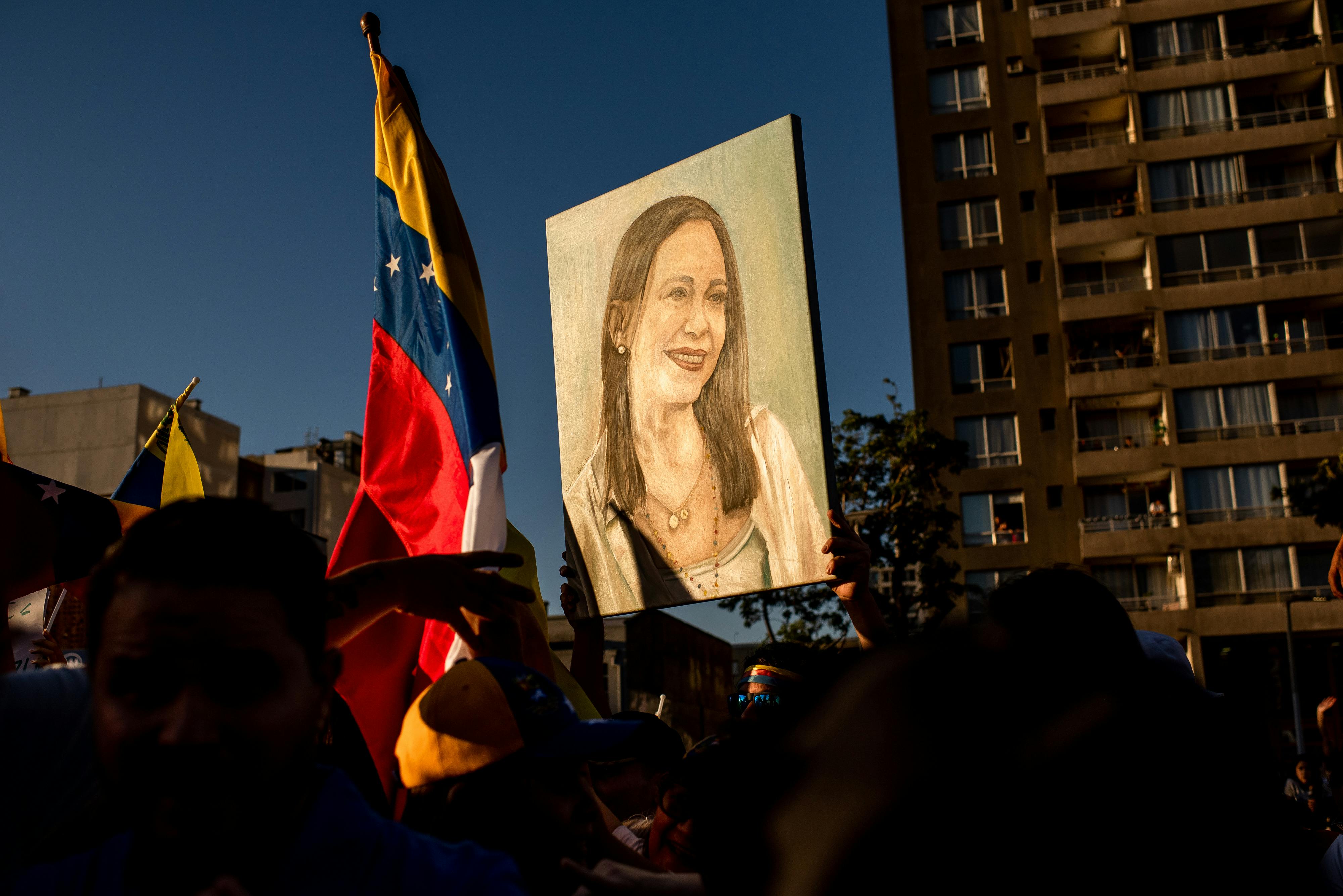 People hold up a painting of Venezuelan opposition leader Maria Corina Machado as well as a Venezuelan flag.