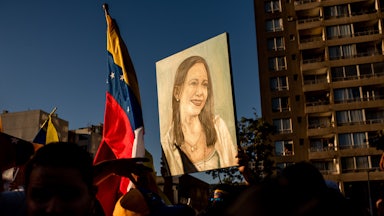 People hold up a painting of Venezuelan opposition leader Maria Corina Machado as well as a Venezuelan flag.