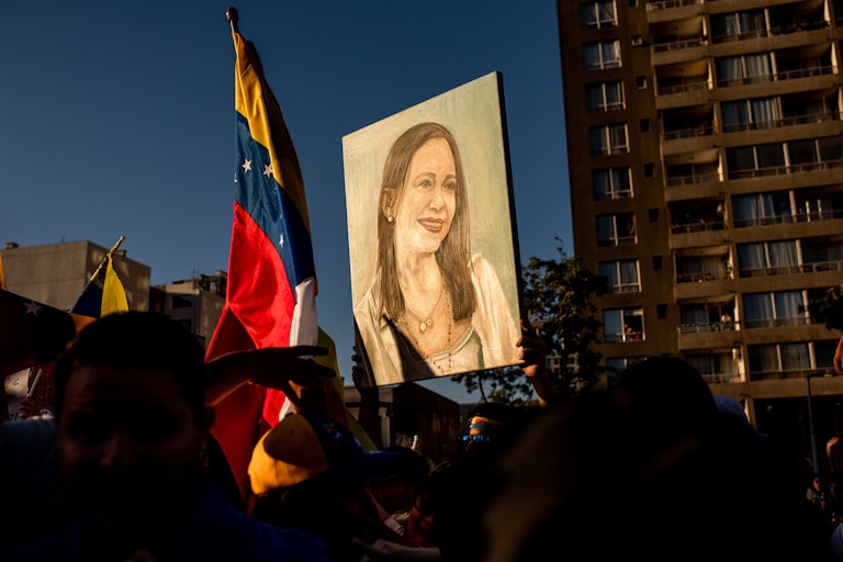 People hold up a painting of Venezuelan opposition leader Maria Corina Machado as well as a Venezuelan flag.