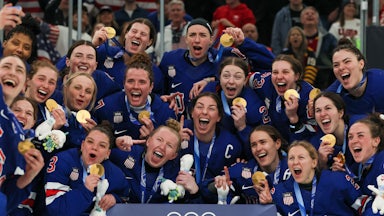 The U.S. women's hockey team poses with their gold medals at the Milan Olympics
