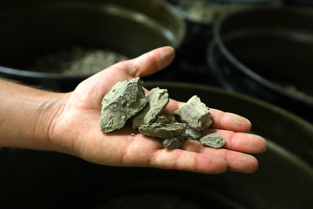 An open hand holds pieces of lithium-rich clay.
