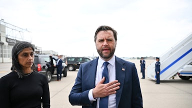 JD Vance speaks with a hand over his chest as his wife Usha zones out. The two are at an airport outside the plane.
