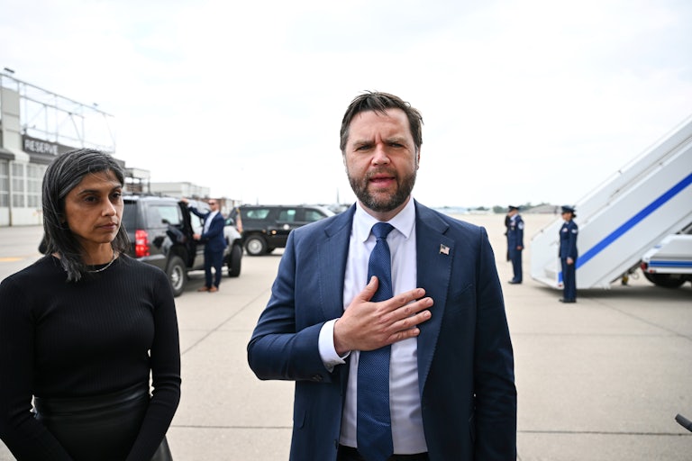 JD Vance speaks with a hand over his chest as his wife Usha zones out. The two are at an airport outside the plane.