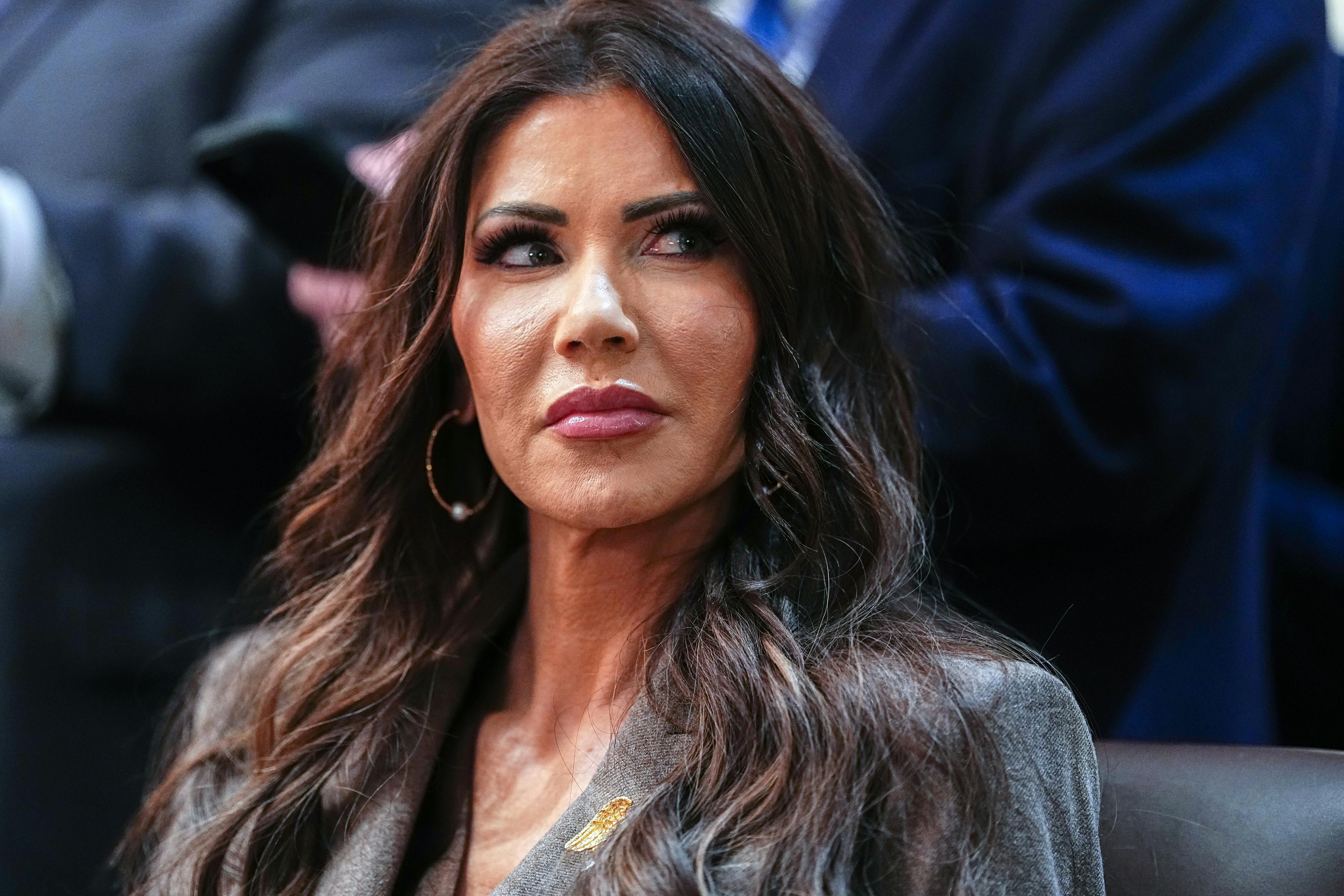 Homeland Security Secretary Kristi Noem looks to the side while sitting at an event