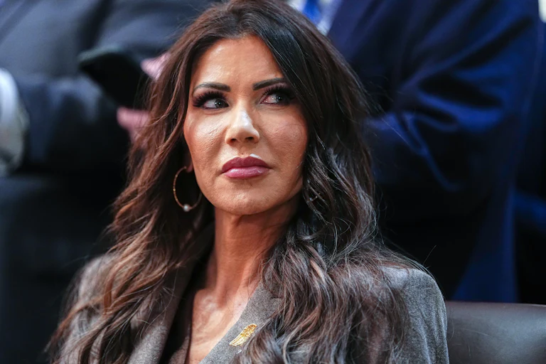 Homeland Security Secretary Kristi Noem looks to the side while sitting at an event