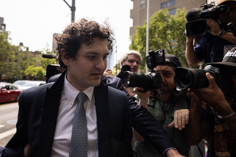 Sam Bankman-Fried walks as cameras surround him