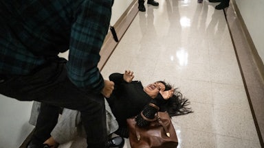 A woman screams on the ground after she is tackled by an ICE agent.