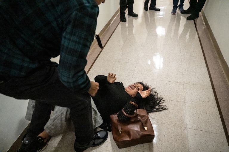A woman screams on the ground after she is tackled by an ICE agent.