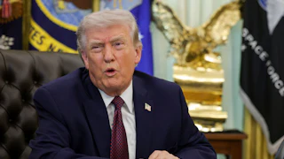 President Donald Trump speaking at his desk in the Oval Office of the White House.