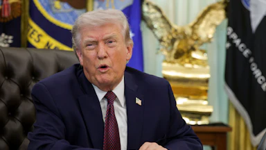 President Donald Trump speaking at his desk in the Oval Office of the White House.