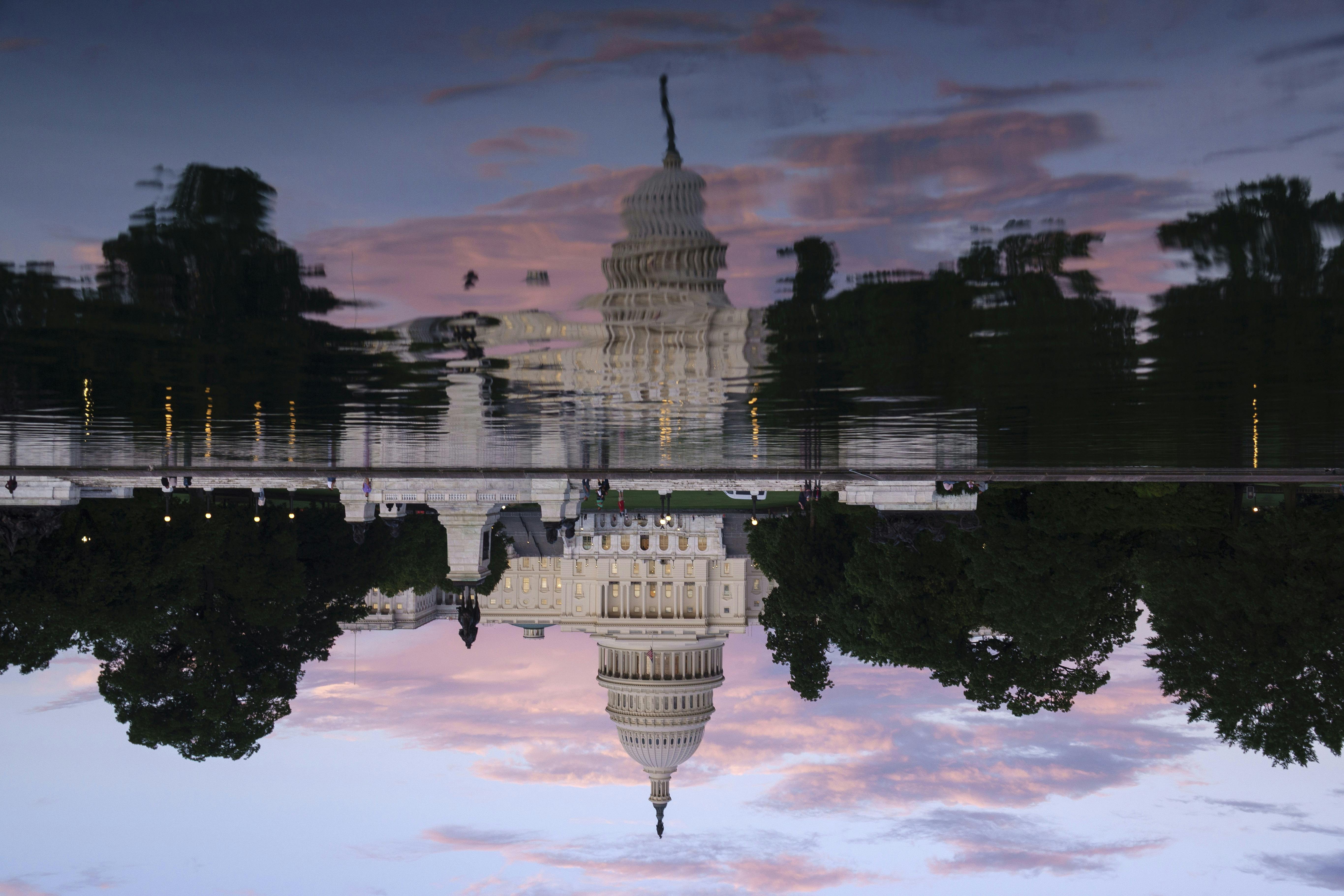 The U.S. Capitol Building is reflected in the Capitol Reflecting Pool at sunset.