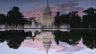 The U.S. Capitol Building is reflected in the Capitol Reflecting Pool at sunset.