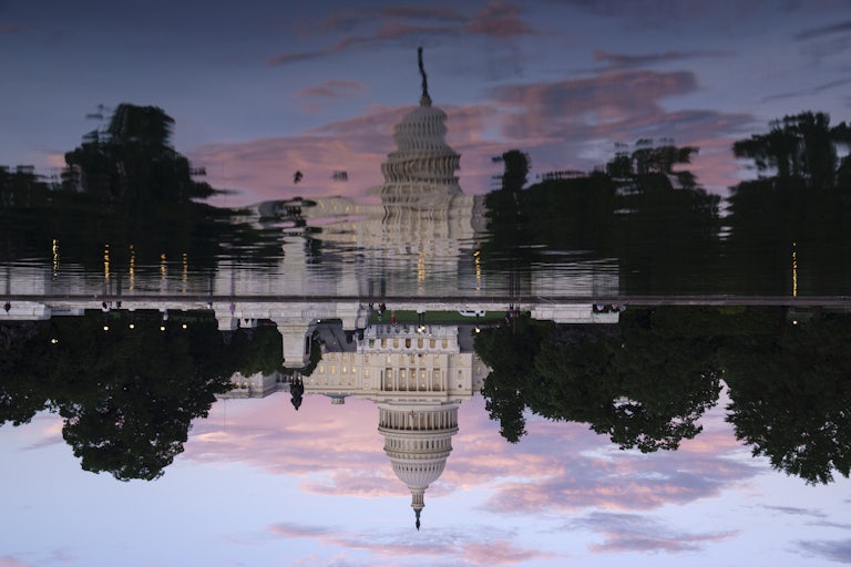 The U.S. Capitol Building is reflected in the Capitol Reflecting Pool at sunset.