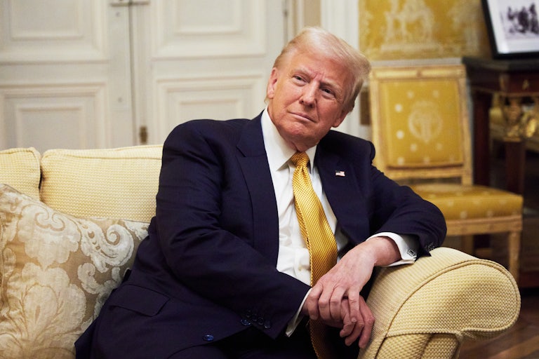 Donald Trump rests on a yellow couch, leaning over on the armrest