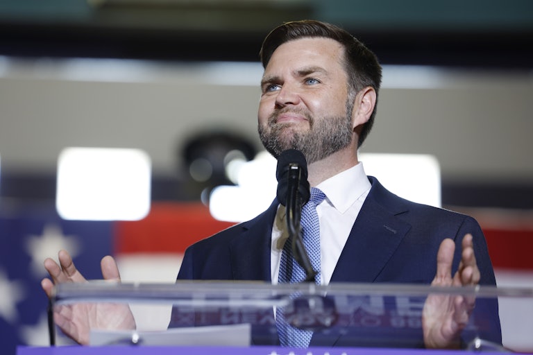 J.D. Vance smiles while speaking at a mic, his hands spread out