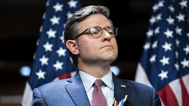 Mike Johnson stands, carrying a folder, with his lips pressed together.