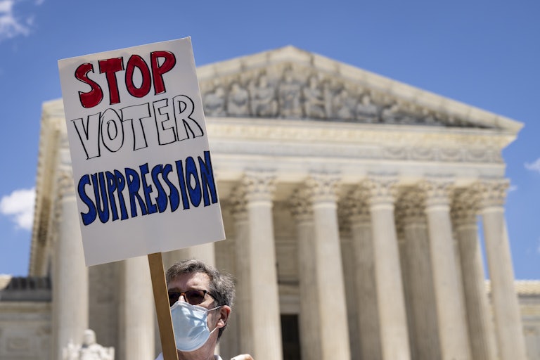 A man in front of the Supreme Court holds a sign that reads "Stop Voter Suppression"