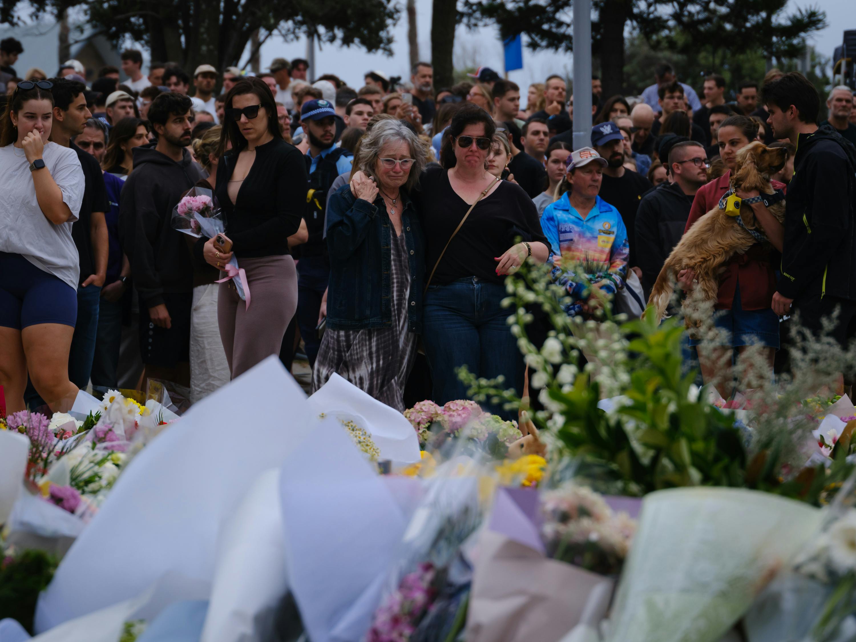 People stand next to a memorial for the victims of the shooting at Bondi Beach